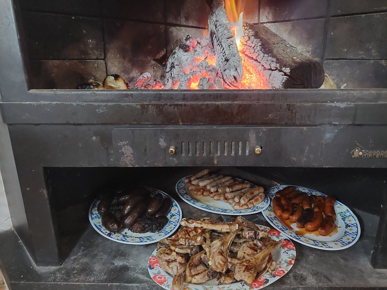 Carnes y embutidos asándose en un horno de leña