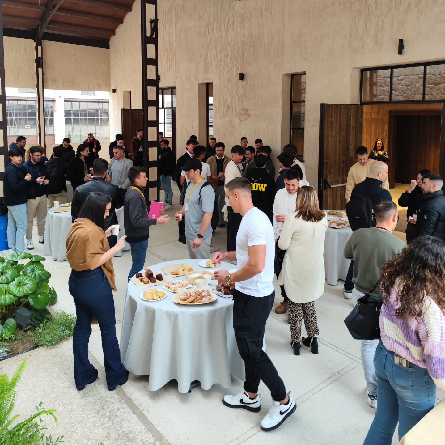 Invitados en un cóctel de pie en un espacio de piedra en Alcoy con mesa de aperitivos