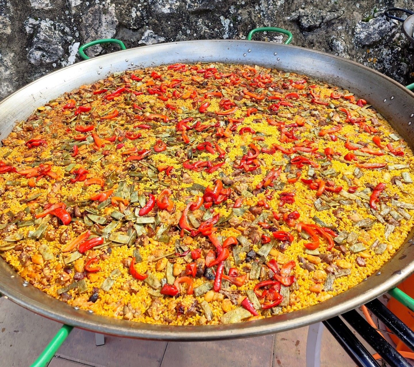 Paella gigante de verduras con pimiento rojo cocinada al aire libre en Muro de Alcoy