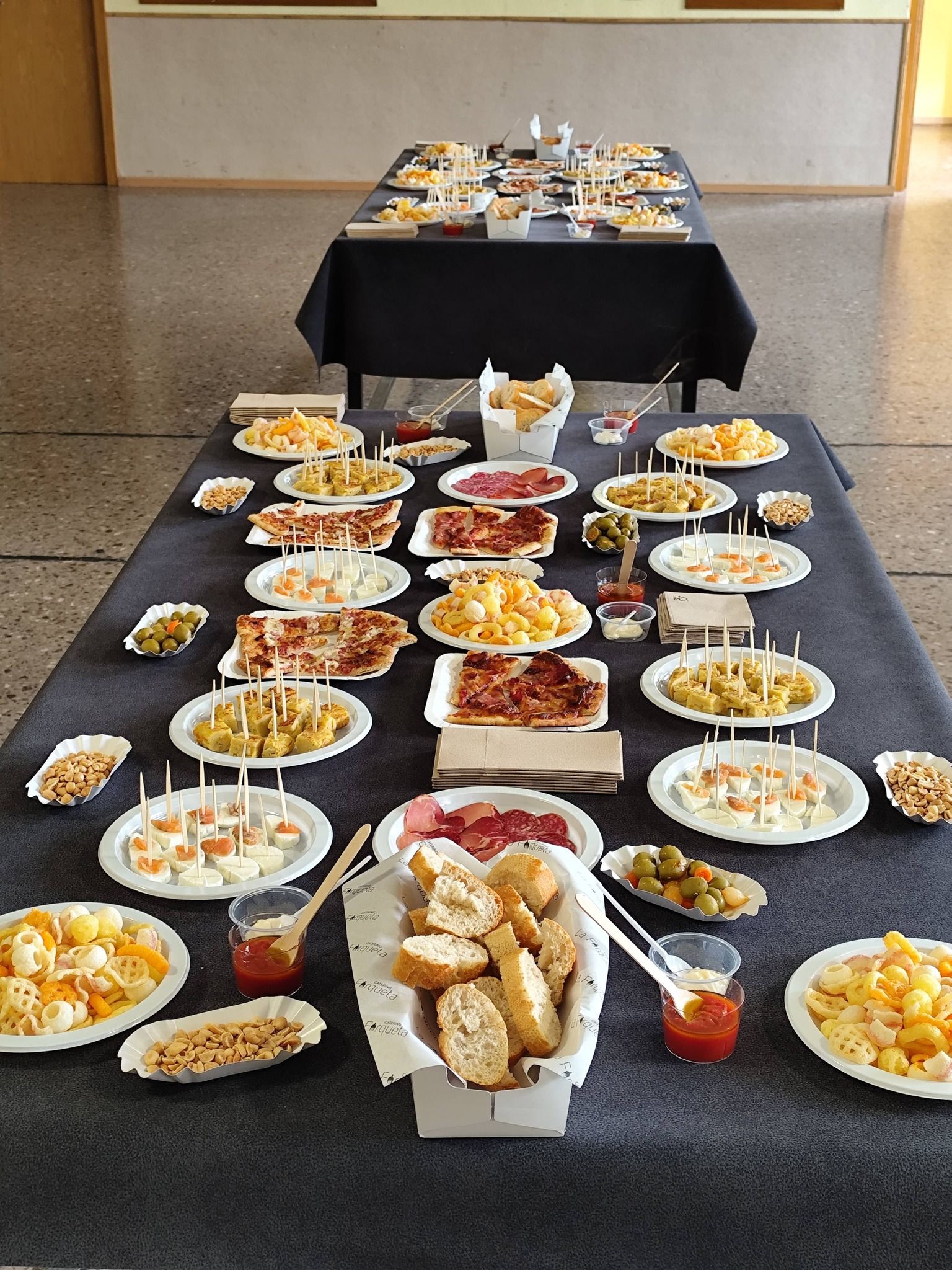 Mesa larga de aperitivos con tapas, canapés y patatas lista para un evento